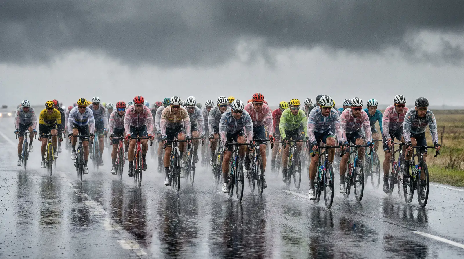 Pelotón ciclista bajo lluvia intensa en carretera abierta